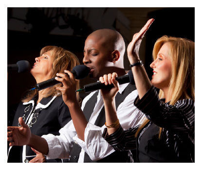 Trois chanteurs se produisant avec des microphones sur scène.