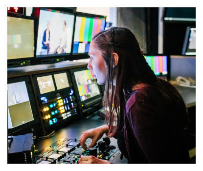Femme opérant des équipements de traitement vidéo dans une salle de contrôle.