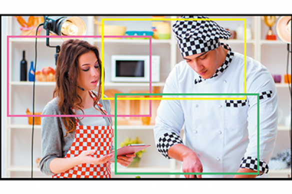 Camera framing a cooking show scene with a male chef and female assistant.