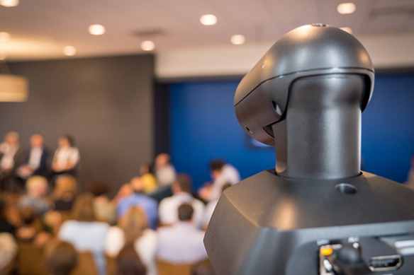 PTZ camera in focus with blurred audience and stage in background.