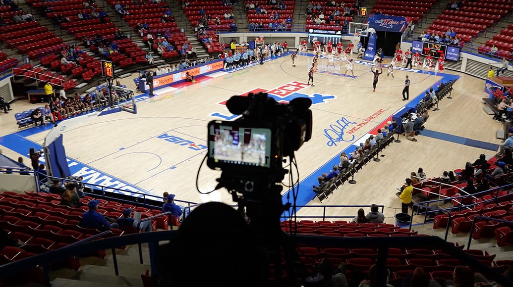 High angle view of a basketball court with a video camera and people scattered around.